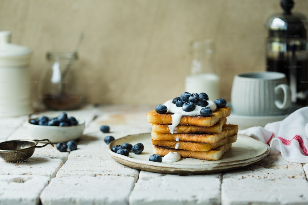 a stack of pancakes with blueberries and cream on a plate