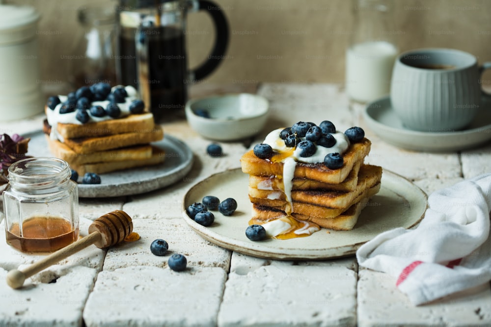 a stack of pancakes with blueberries and whipped cream