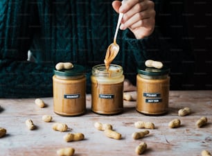 a person holding a spoon in a jar of peanut butter