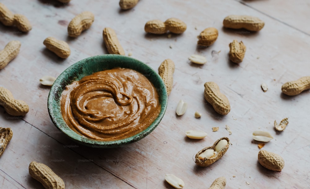 a bowl of peanut butter surrounded by peanuts