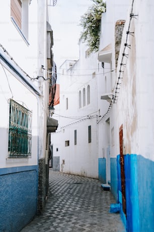 a narrow alleyway with white buildings and blue trim