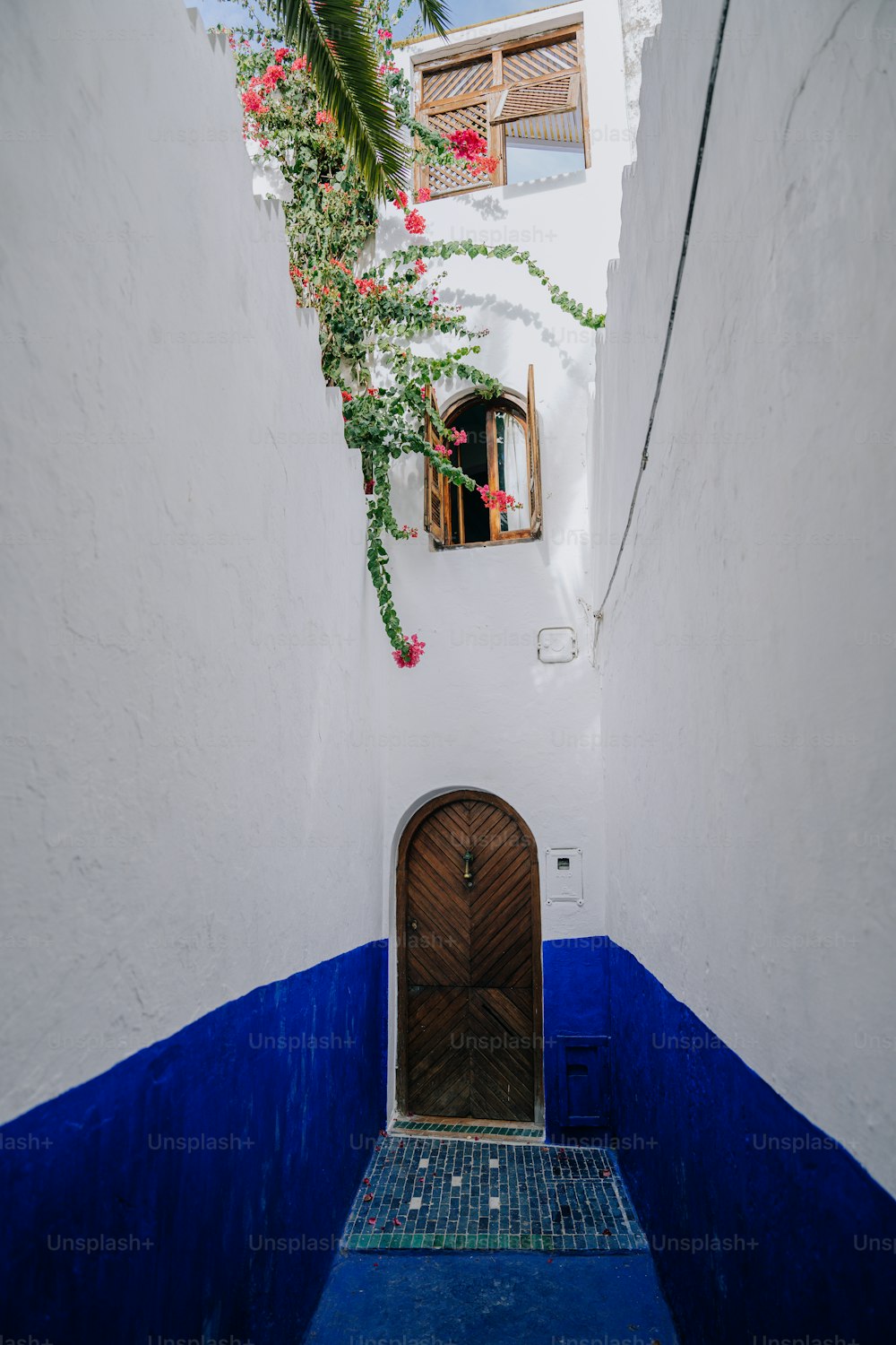 a narrow alleyway with a wooden door and tiled floor
