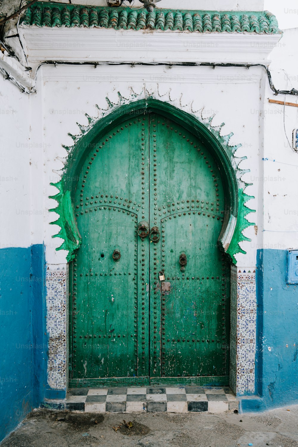 a large green door with spikes on it