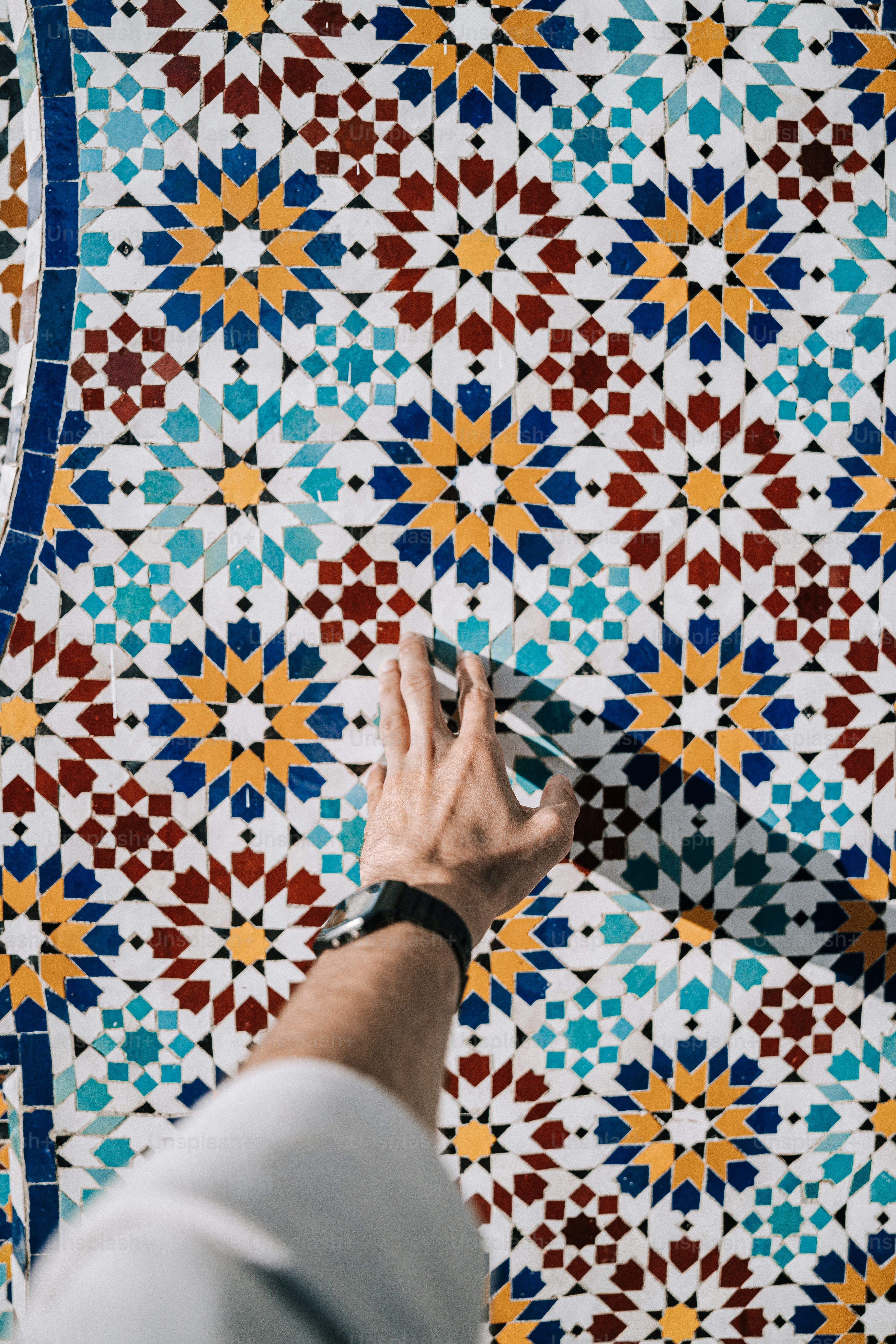 a person painting a colorful tile wall with a brush