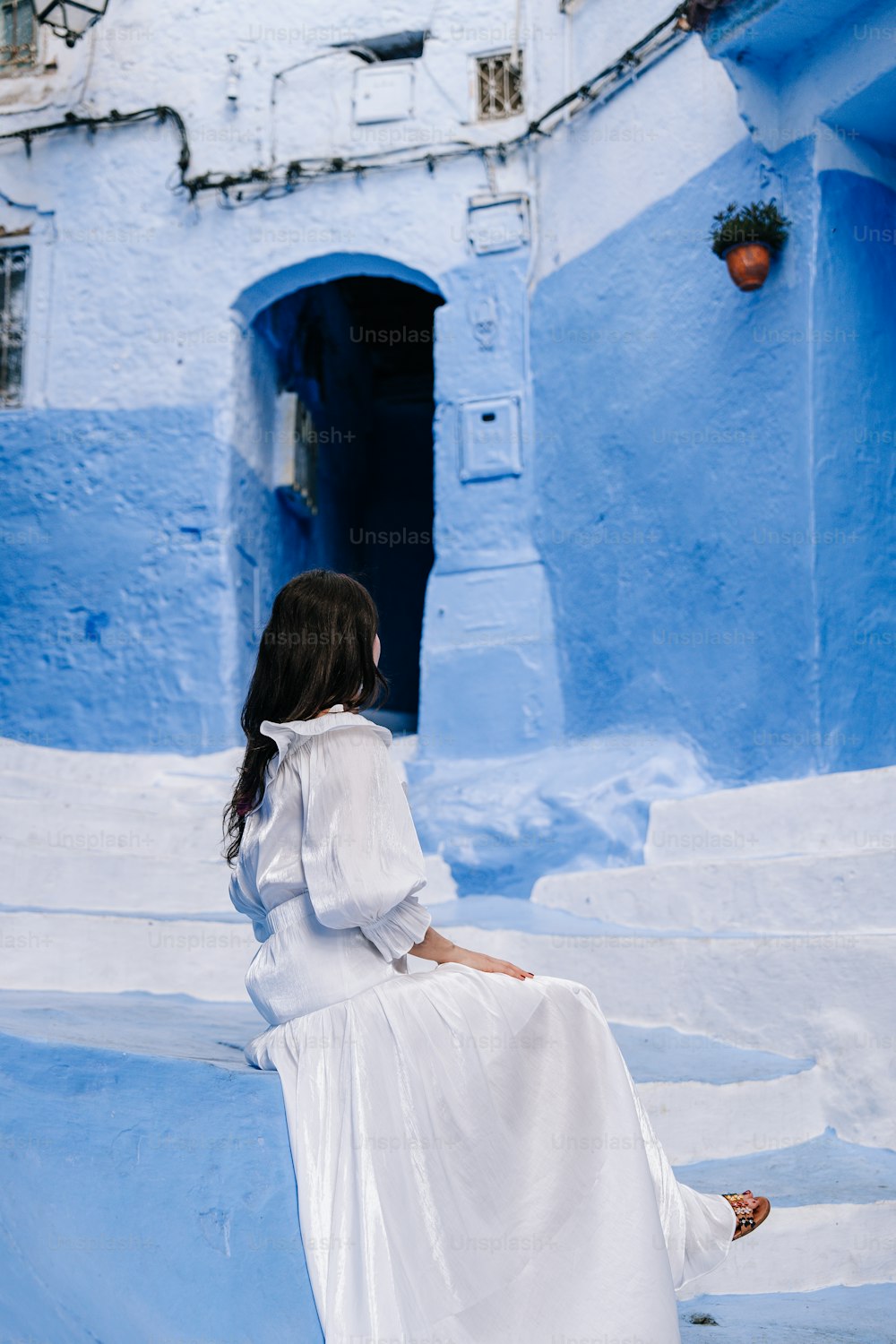 a woman in a white dress sitting on steps
