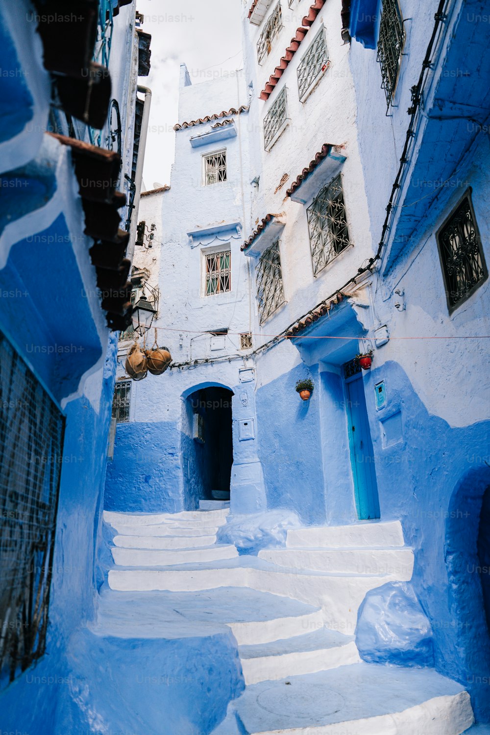 a narrow alleyway with blue buildings and steps