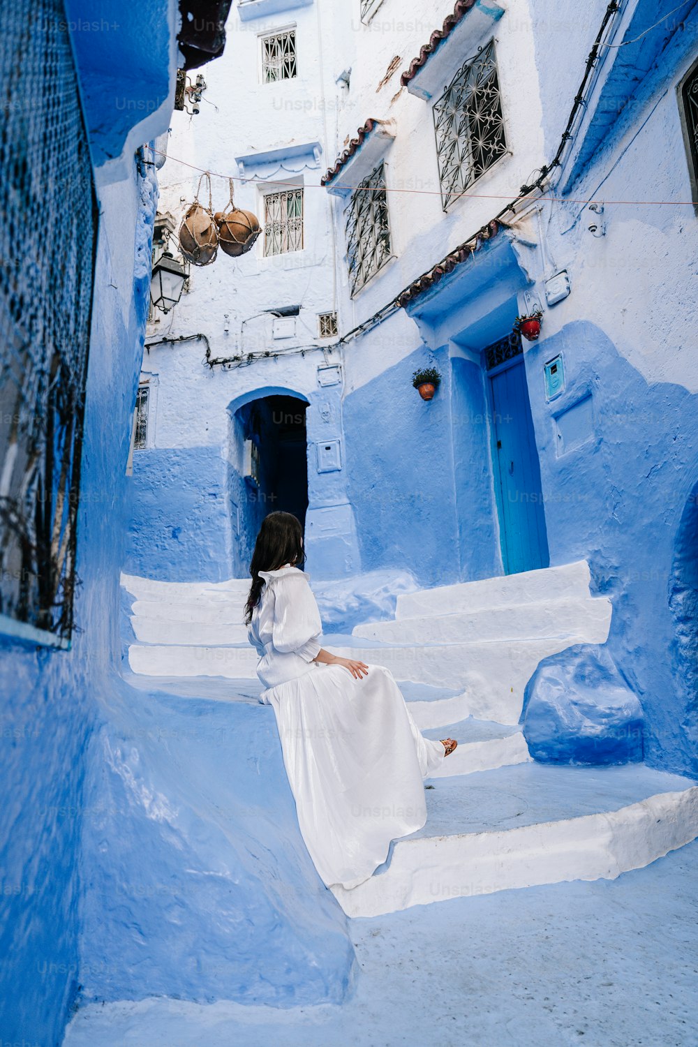 흰 드레스를 입은 여성이 계단에 앉아 있다