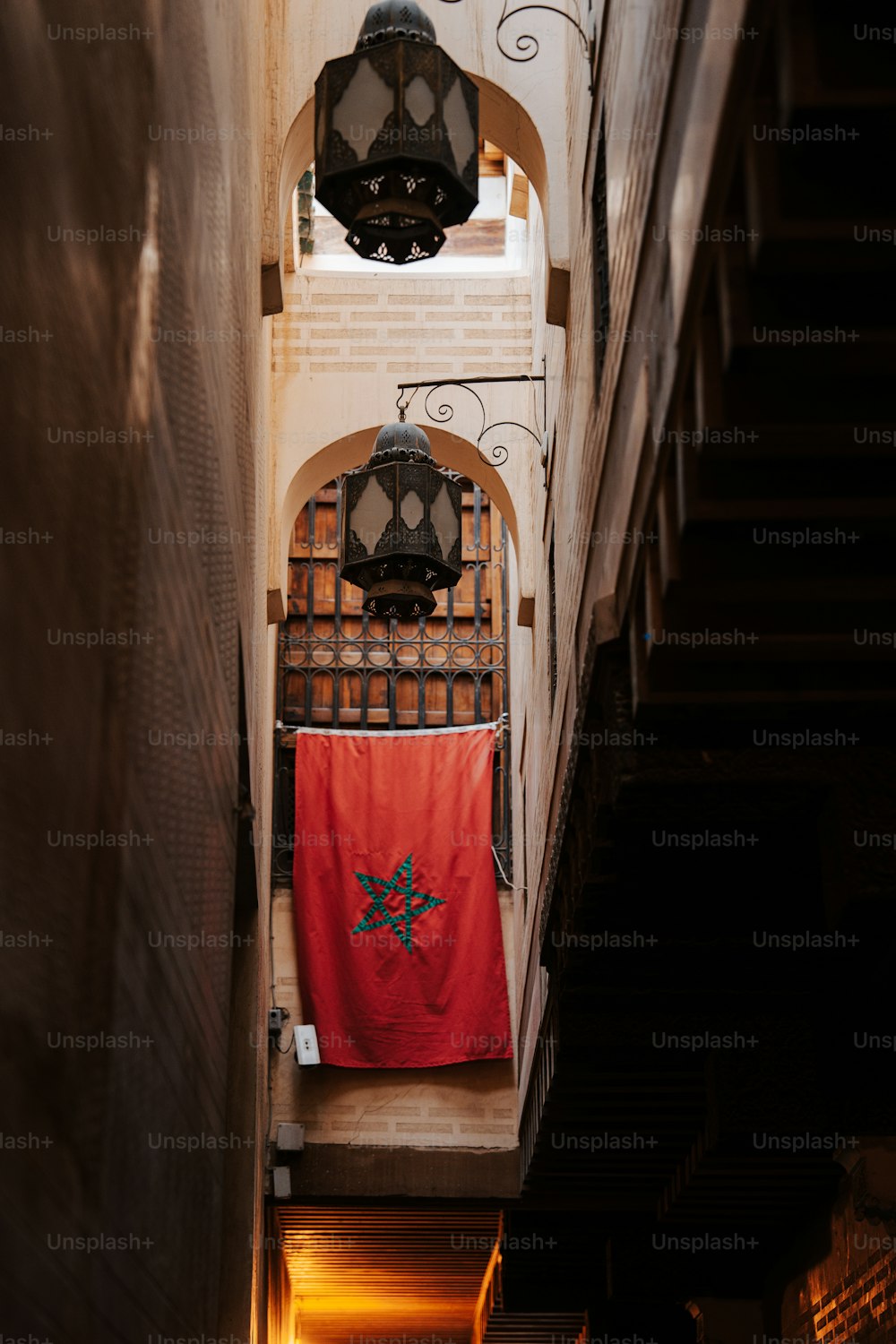 a narrow alleyway with a red flag hanging from the ceiling