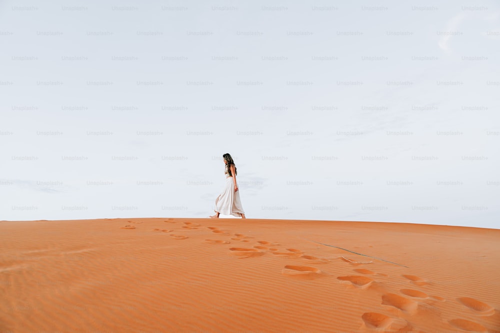una mujer con un vestido blanco caminando por un desierto