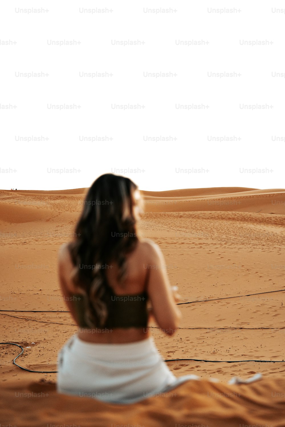 a woman sitting in the middle of a desert