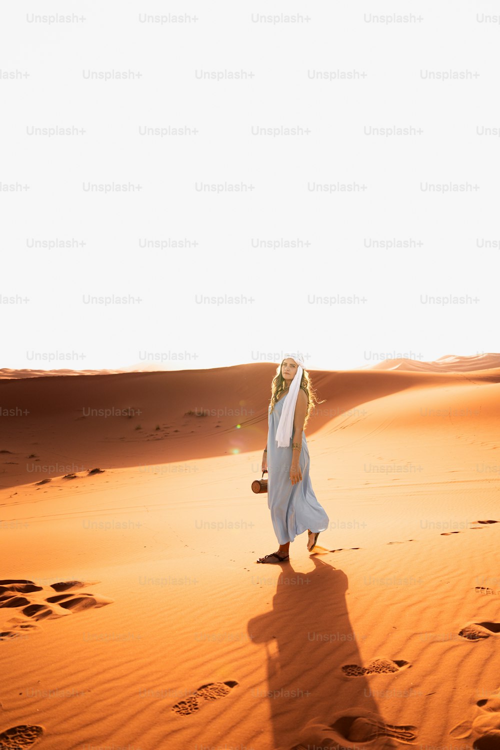 흰 드레스를 입은 여자가 사막을 가로질러 걷고 있다