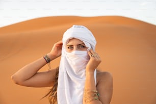 a woman wearing a white head covering in the desert