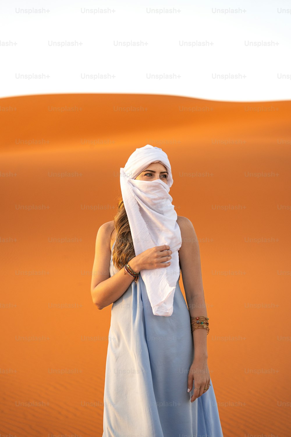 Eine Frau in einem blauen Kleid steht in der Wüste
