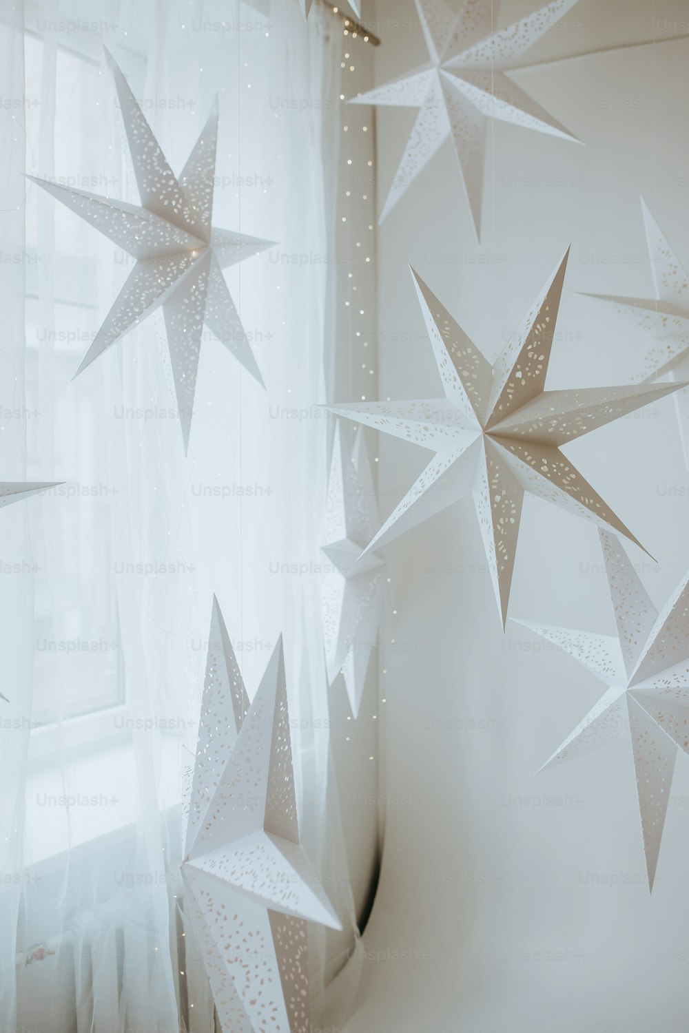 una finestra con una tenda e alcune stelle di carta appese ad essa