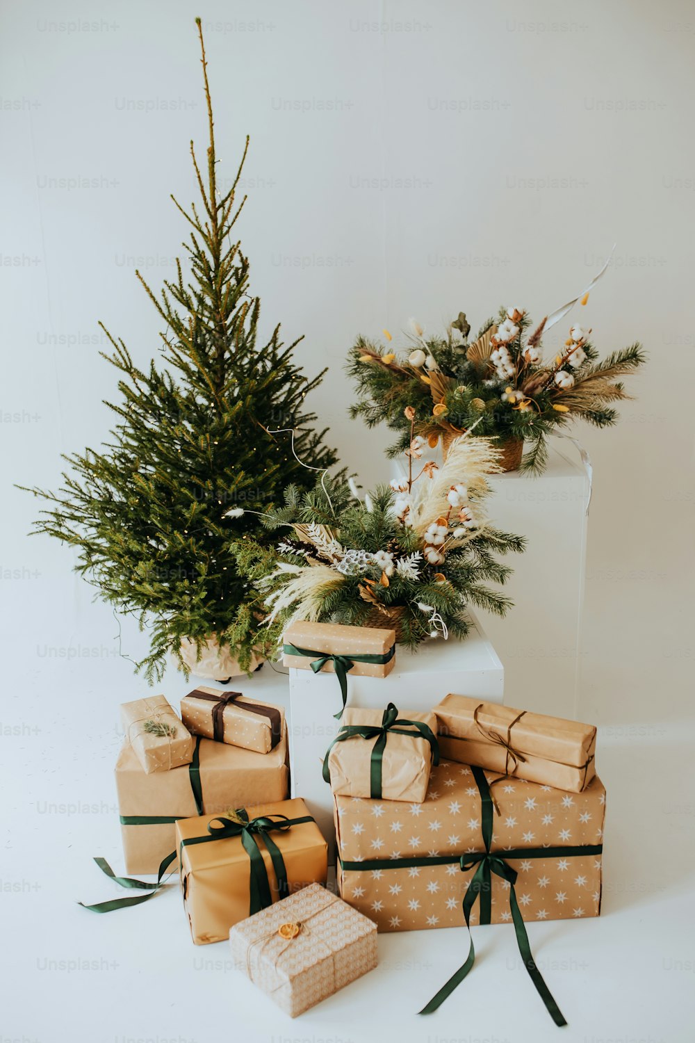 Un grupo de regalos envueltos sentados junto a un árbol de Navidad