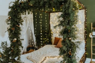 Una cama cubierta de luces navideñas junto a una pared verde
