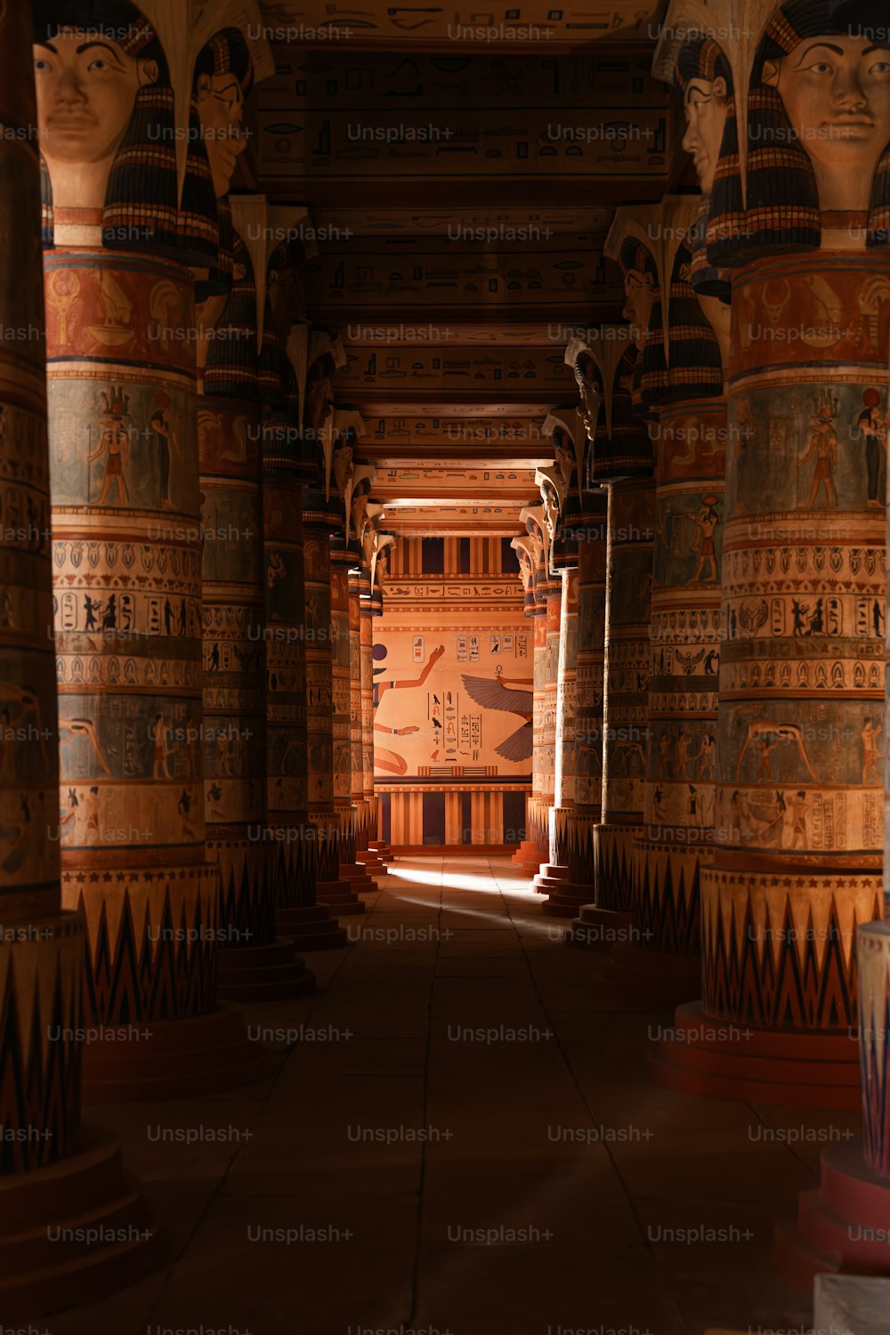 um longo corredor com colunas e pinturas nas paredes
