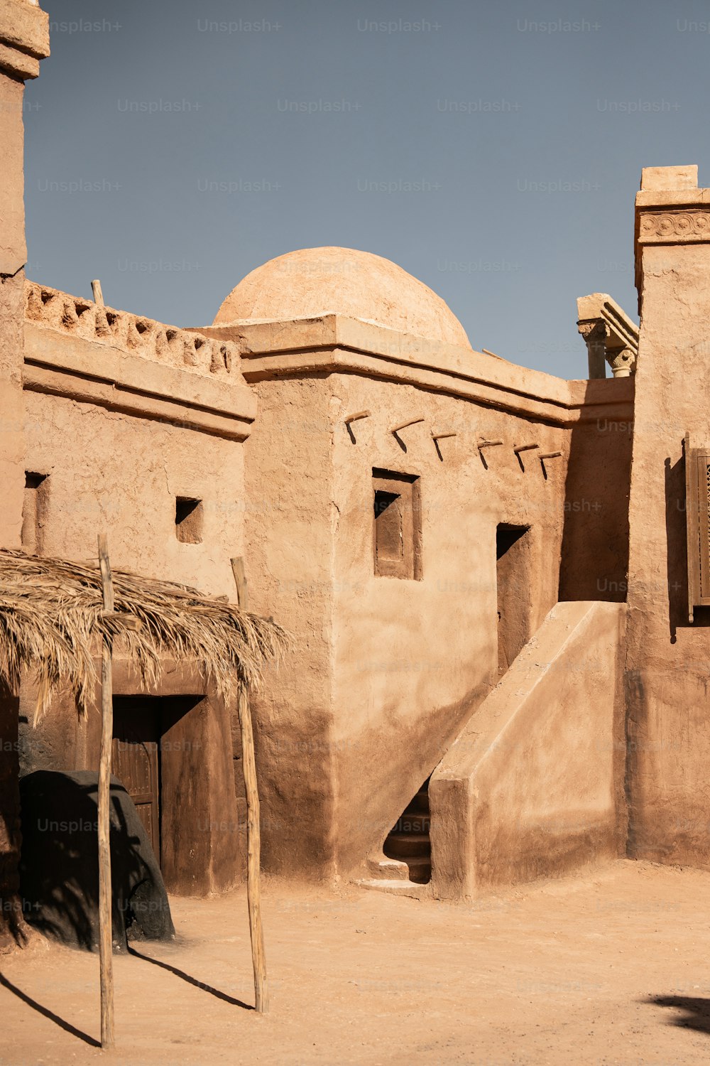 an adobe building with a thatched roof and stairs