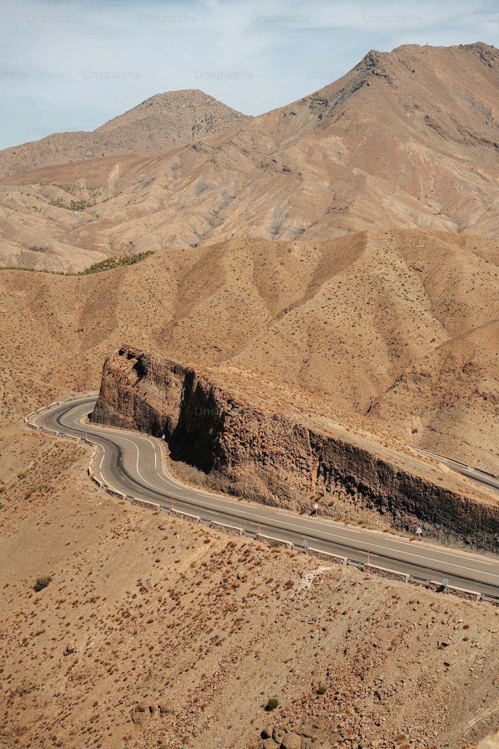 uma estrada no meio de um deserto com montanhas ao fundo