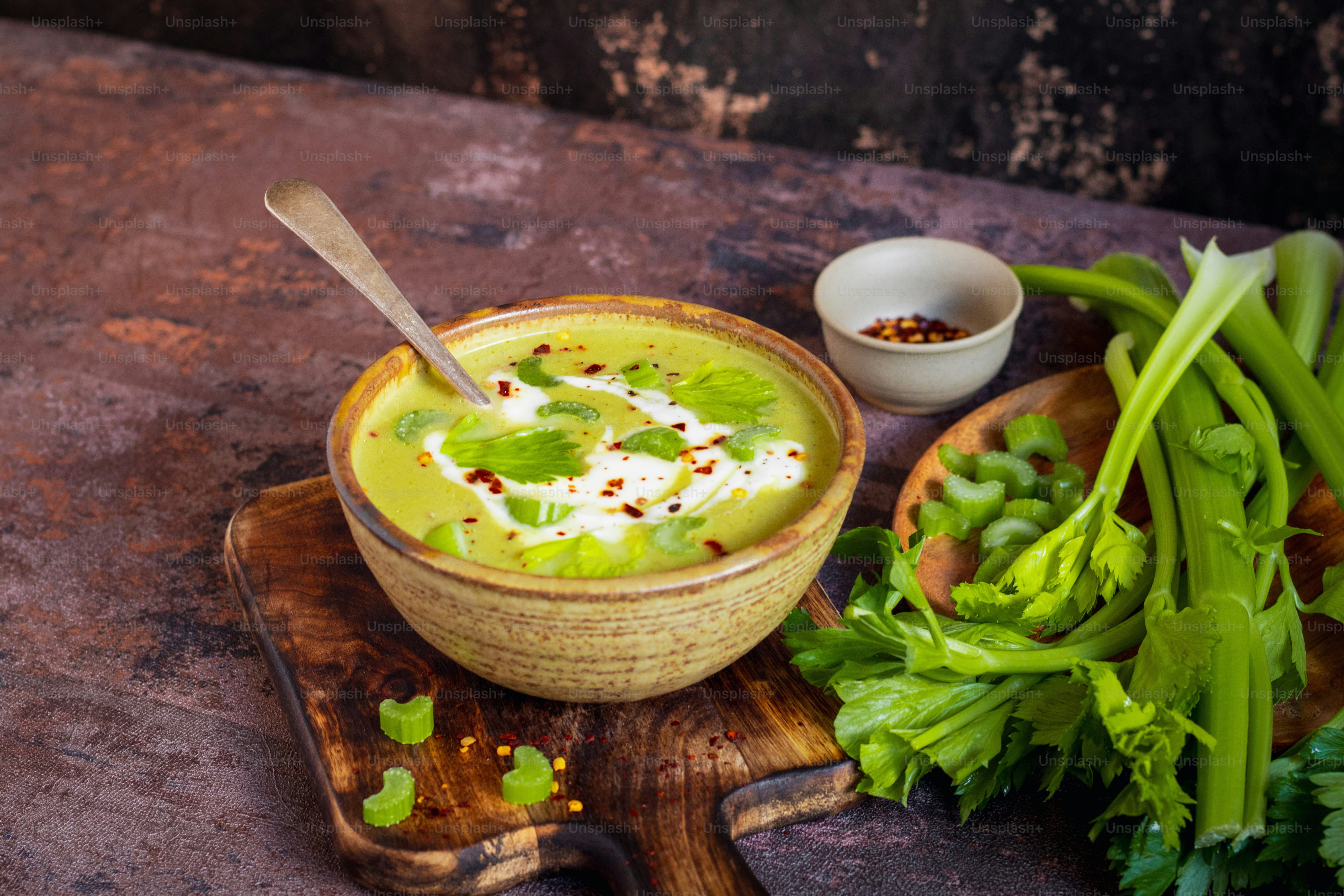 a bowl of soup on a wooden board with a spoon