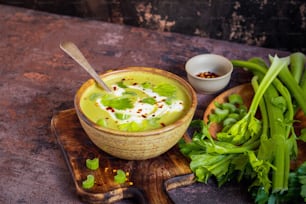 a bowl of soup on a wooden board with a spoon