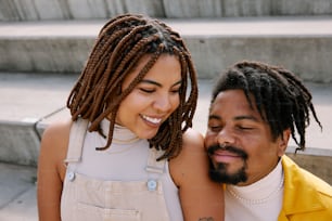 a man with dreadlocks is hugging a woman