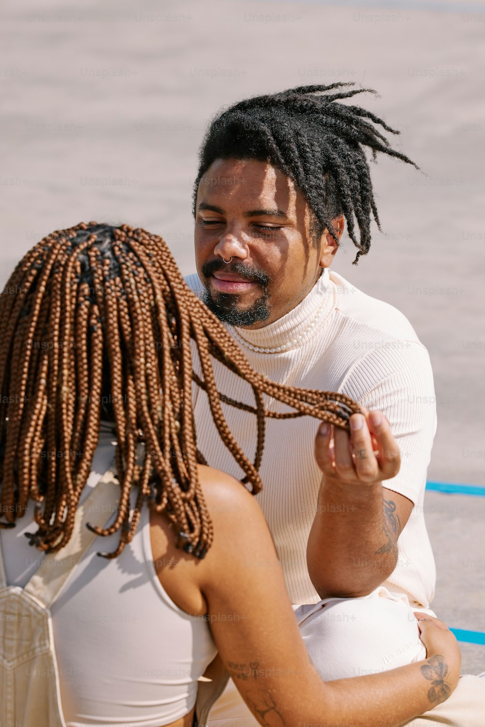 a man with dreadlocks sitting next to a woman
