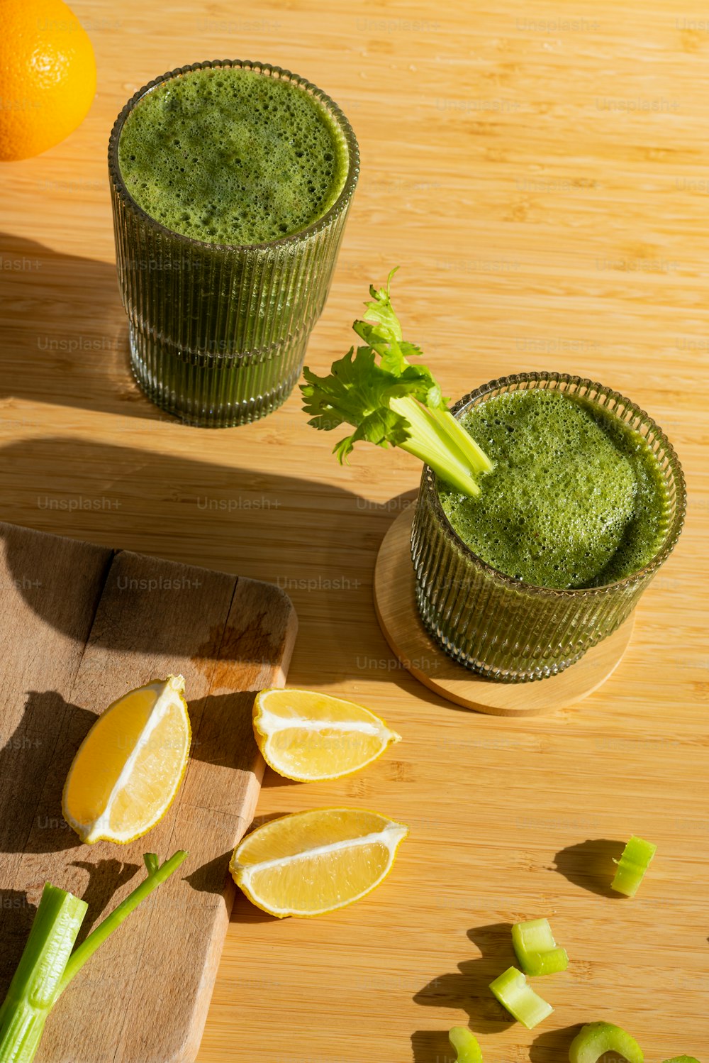 two glasses of green smoothie on a cutting board