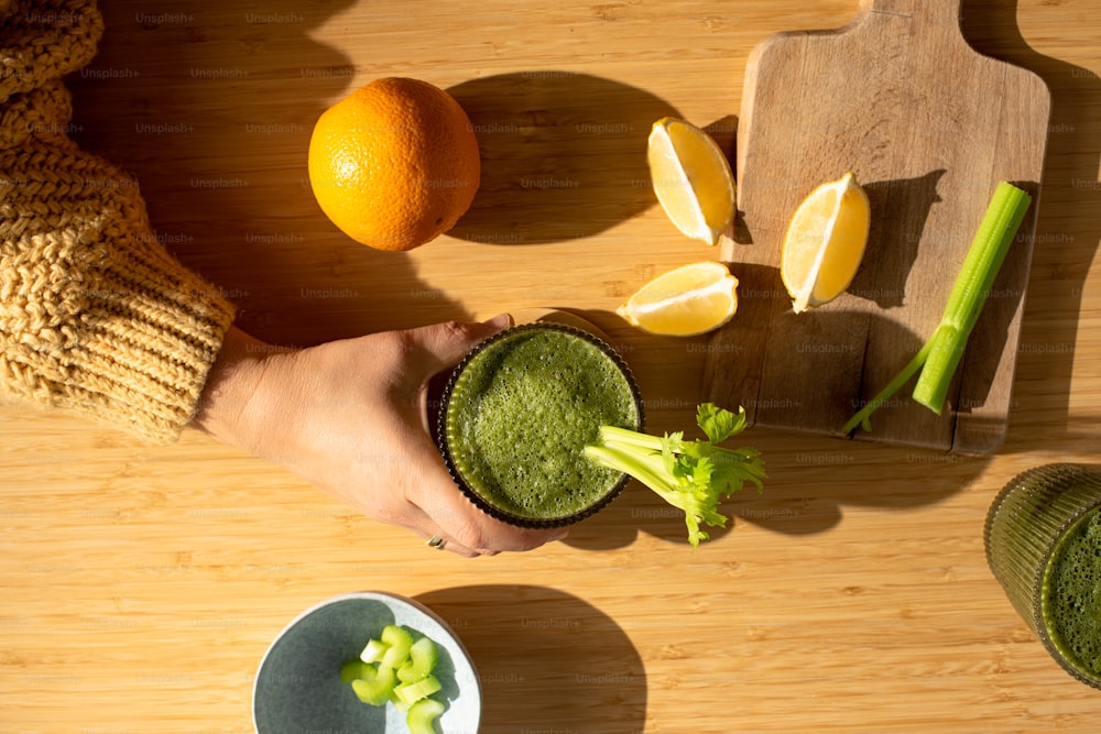 eine Person, die einen grünen Smoothie in der Hand hält