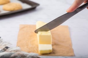 une personne coupant un bloc de beurre avec un couteau