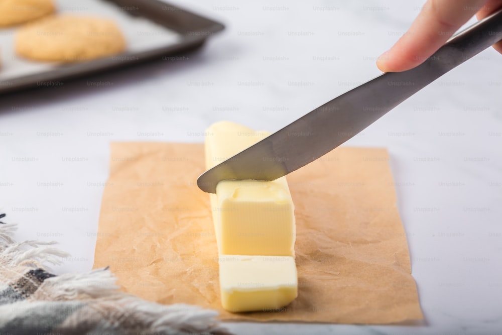 a person cutting a block of butter with a knife