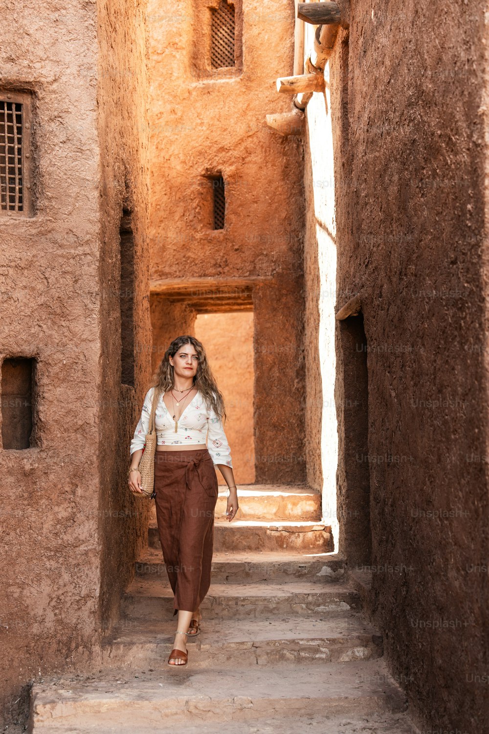 a woman is walking down a narrow alley way