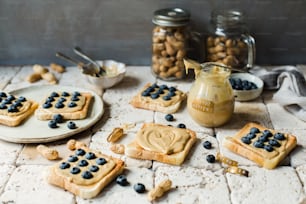 Ein Tisch mit Crackern und Blaubeeren neben einem Glas Erdnussbutter