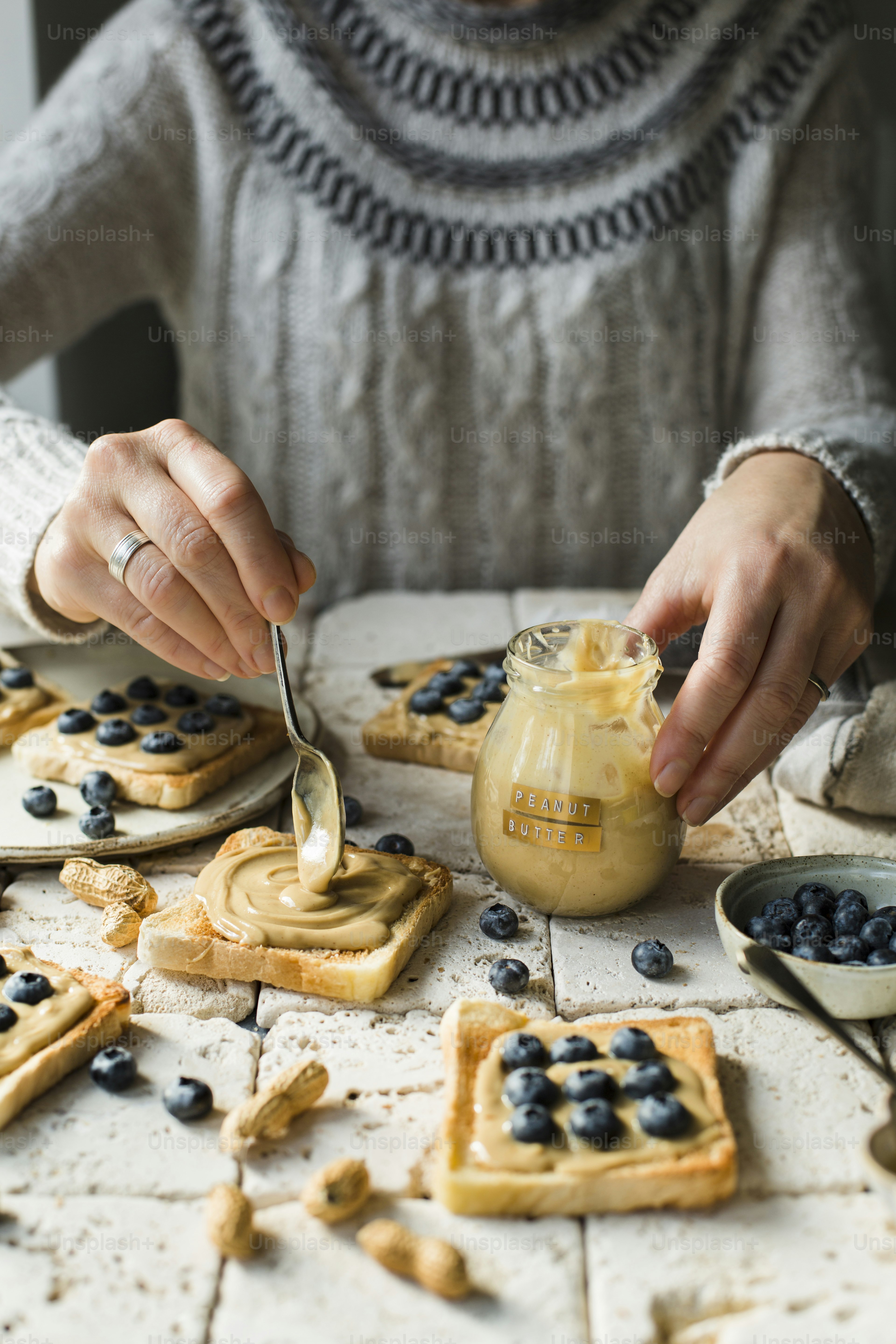 Eine Frau streicht mit einem Löffel Blaubeeren auf Waffeln