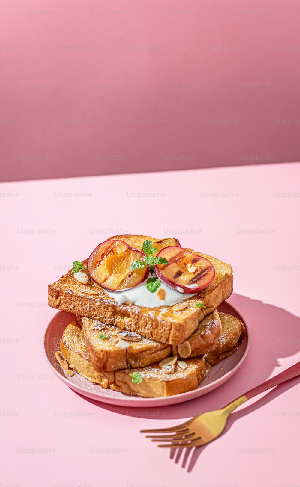 un piatto con un panino e una forchetta su un tavolo rosa