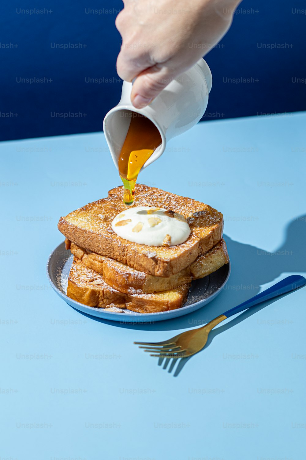 a person pouring syrup on a plate of french toast