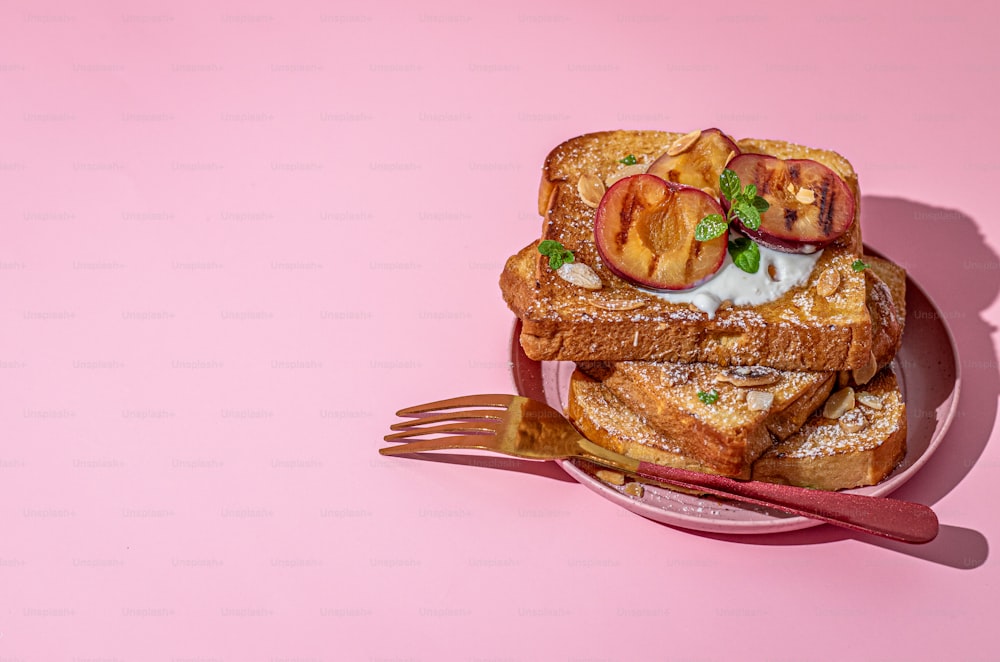 a pink plate topped with french toast and sliced peaches