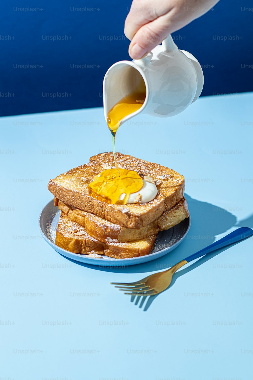 a person pouring syrup on a plate of french toast
