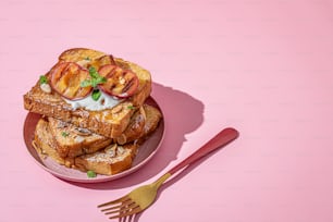 Un plato rosado cubierto con tostadas francesas y duraznos en rodajas