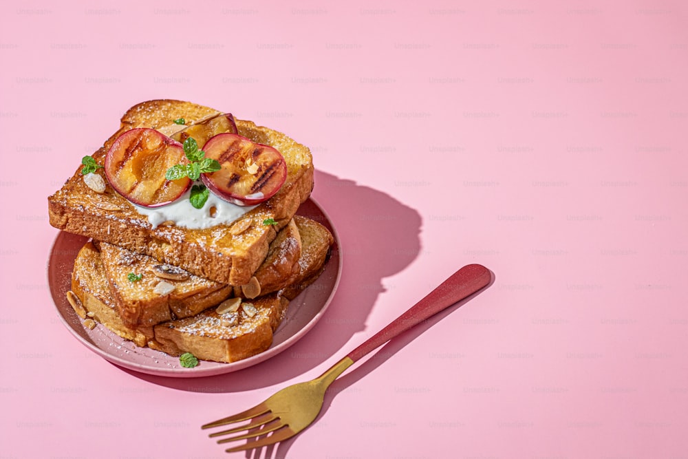 Un piatto rosa condito con toast alla francese e pesche a fette