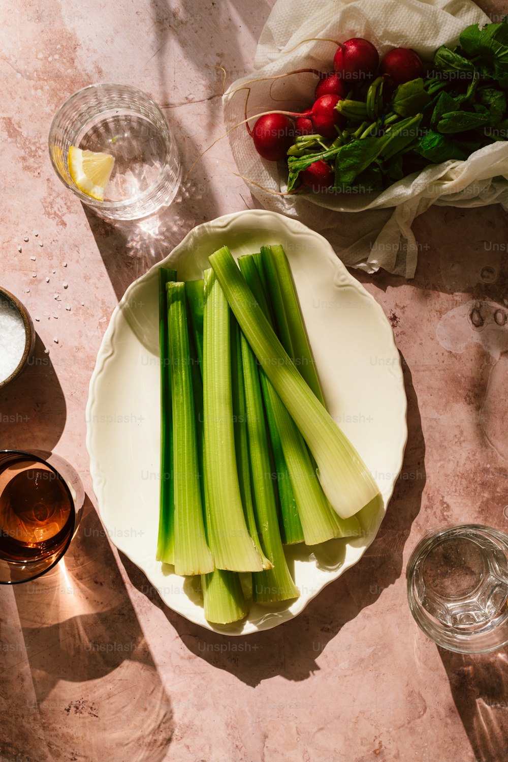 a white plate topped with celery next to a bowl of radishes