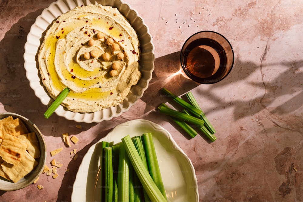 a plate of hummus and green beans next to a bowl of hummus