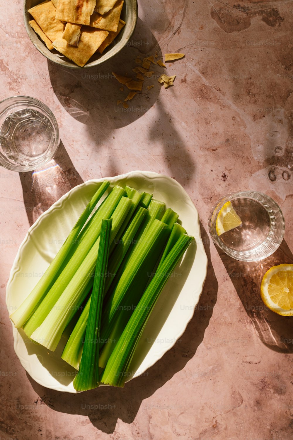 a plate of celery next to a bowl of chips