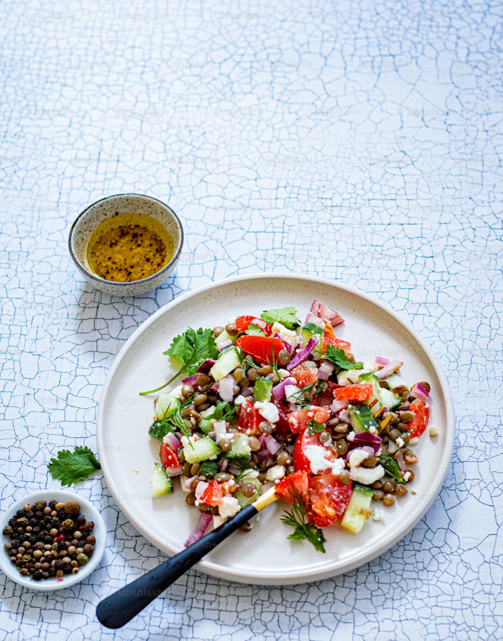 ein weißer Teller mit Salat neben einer Schüssel Oliven