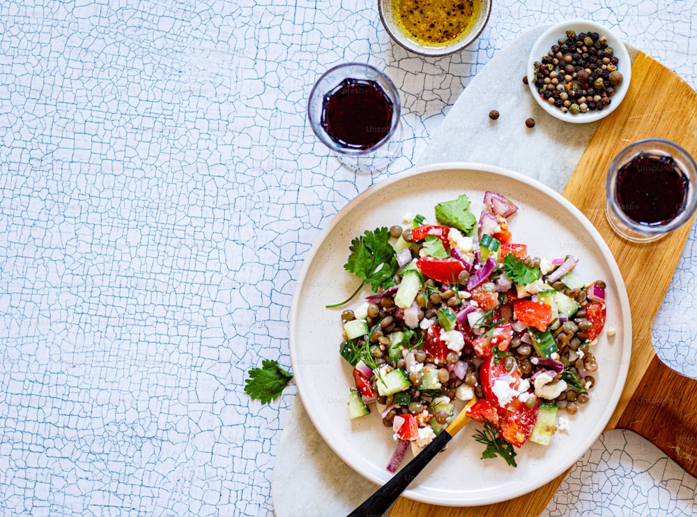 une assiette blanche garnie d’une salade à côté d’un bol d’olives