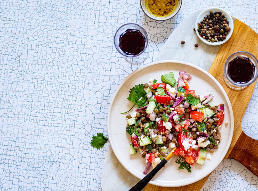 a white plate topped with a salad next to a bowl of olives