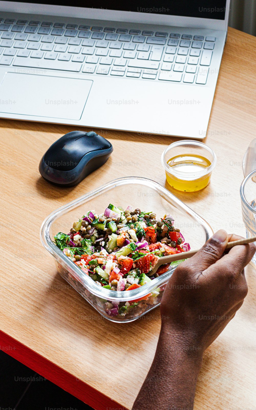 a person is eating a salad in front of a laptop
