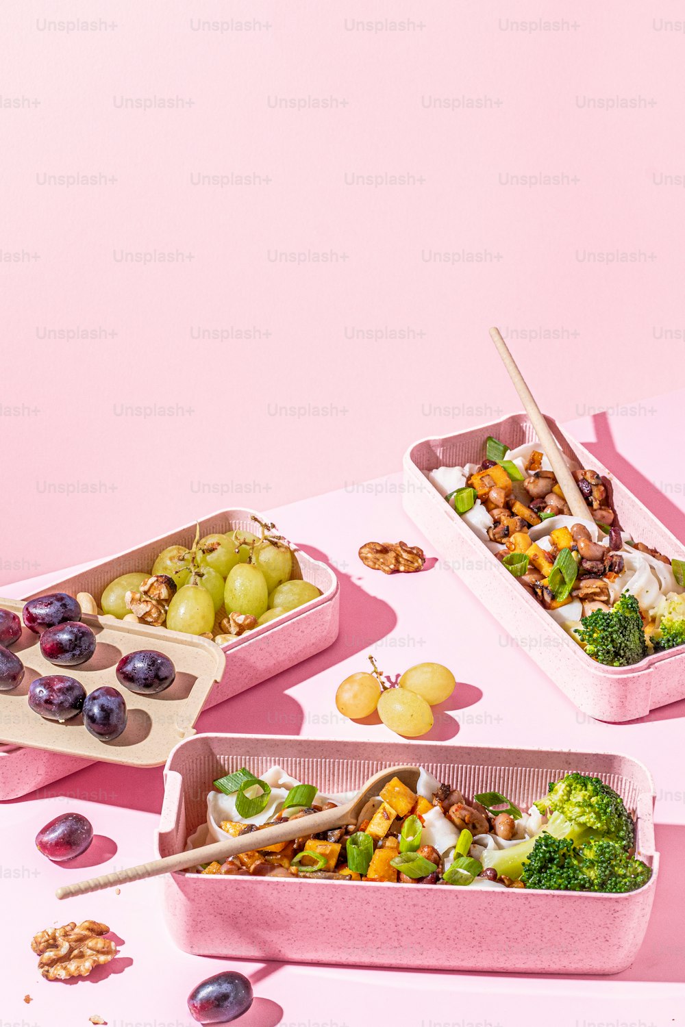 a table topped with pink containers filled with food