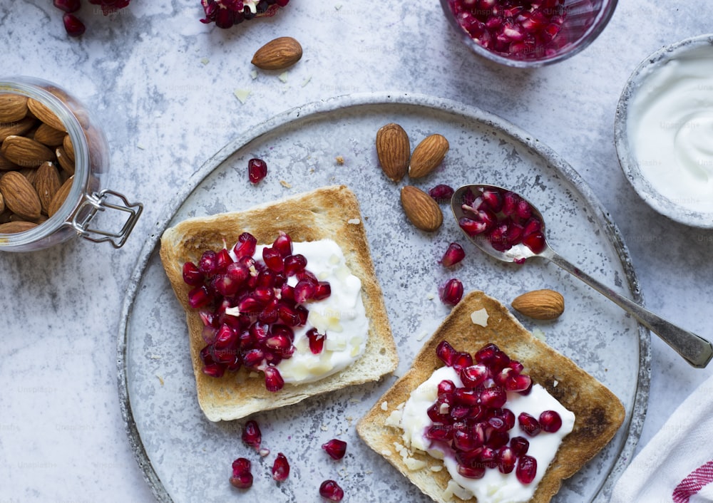 two pieces of toast with whipped cream and pomegranate on top