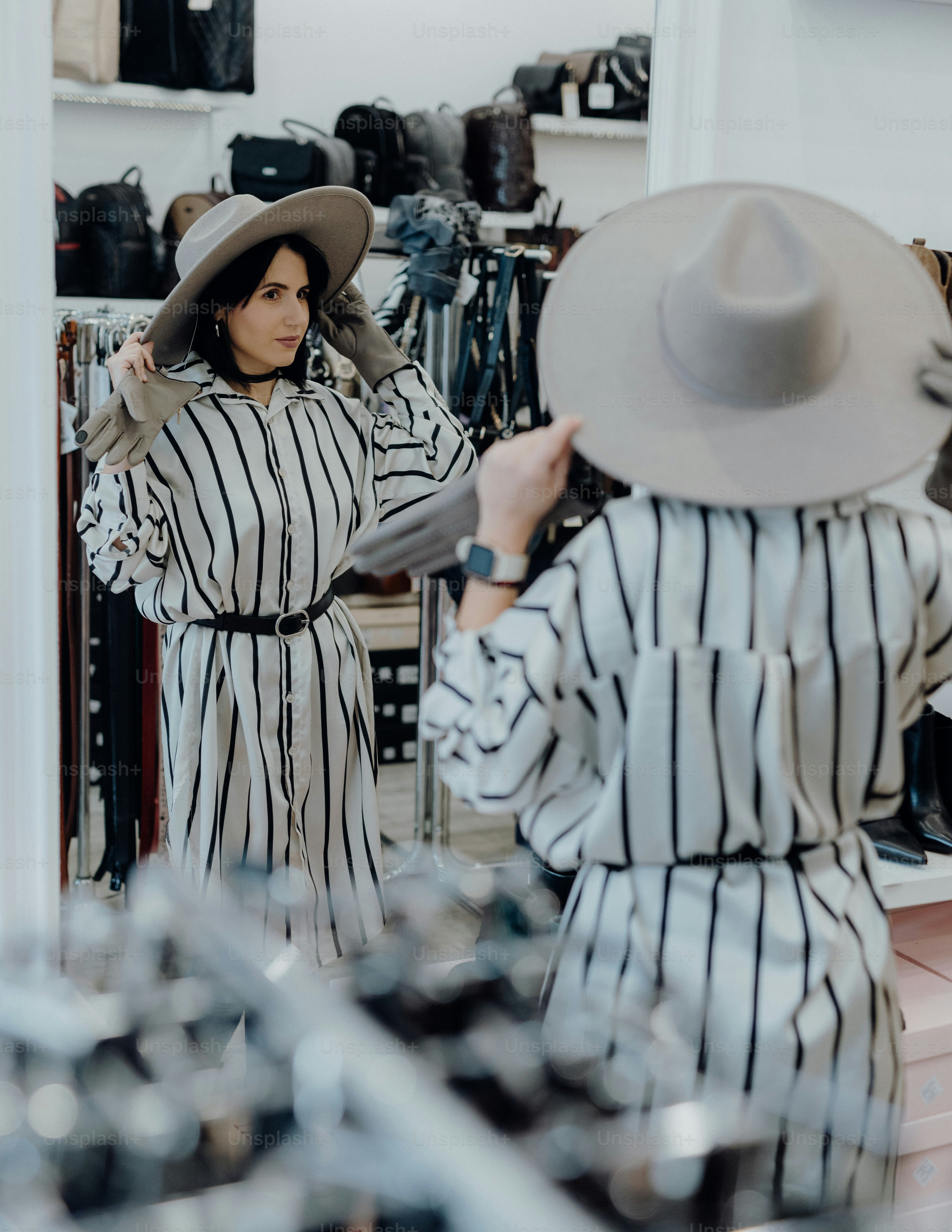 a woman in a hat looking at herself in a mirror